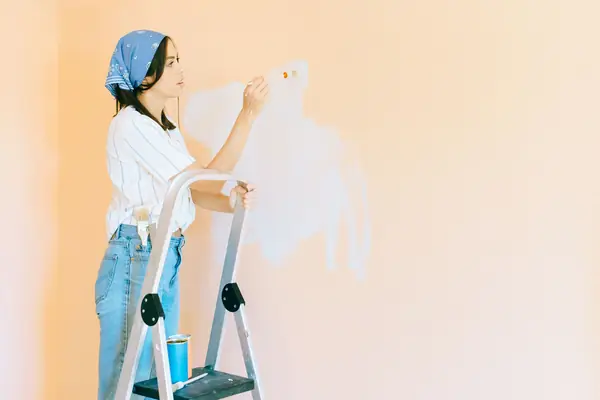 Interior painting in Tallahassee: painter on a stepladder rolling a wall